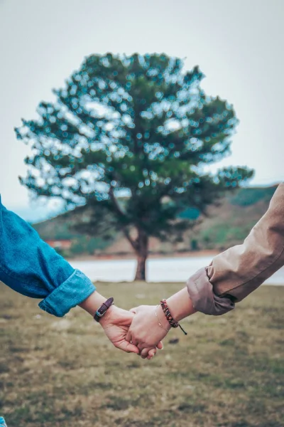 Couple holding hands in front of tree